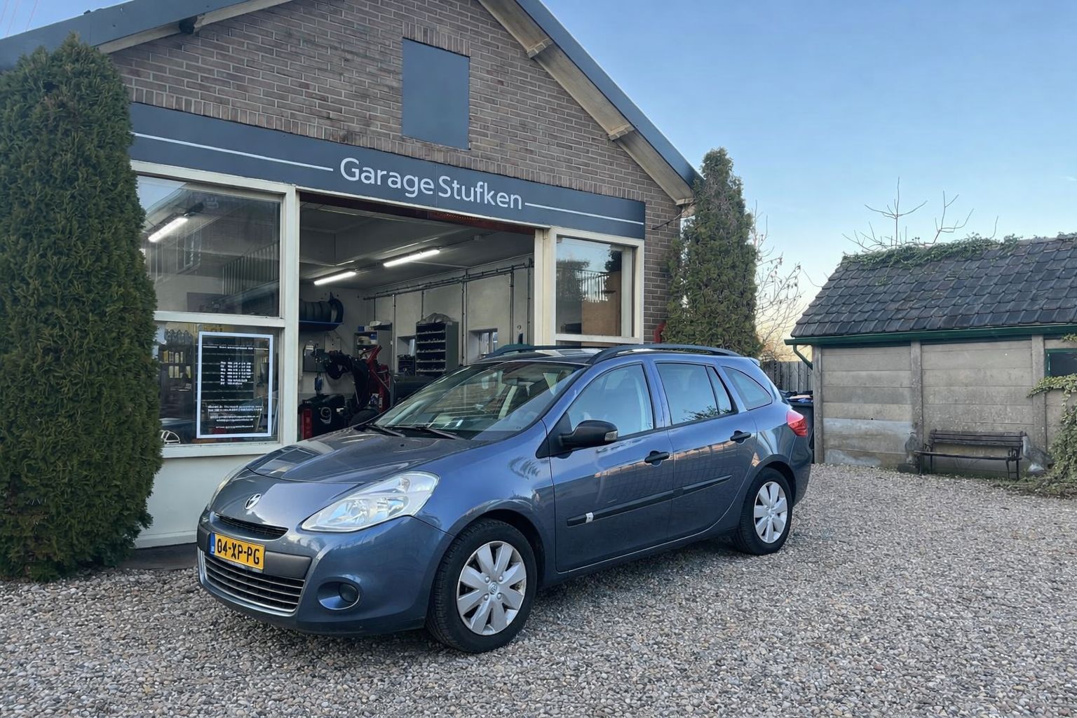Blauwe Renault Clio Station voor de gevel van Garage Stufken