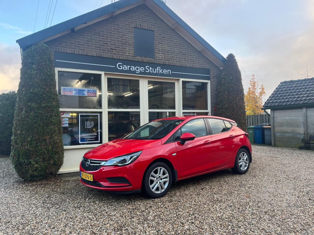 Rode Opel Astra voor de gevel van Garage Stufken met het naambord erboven