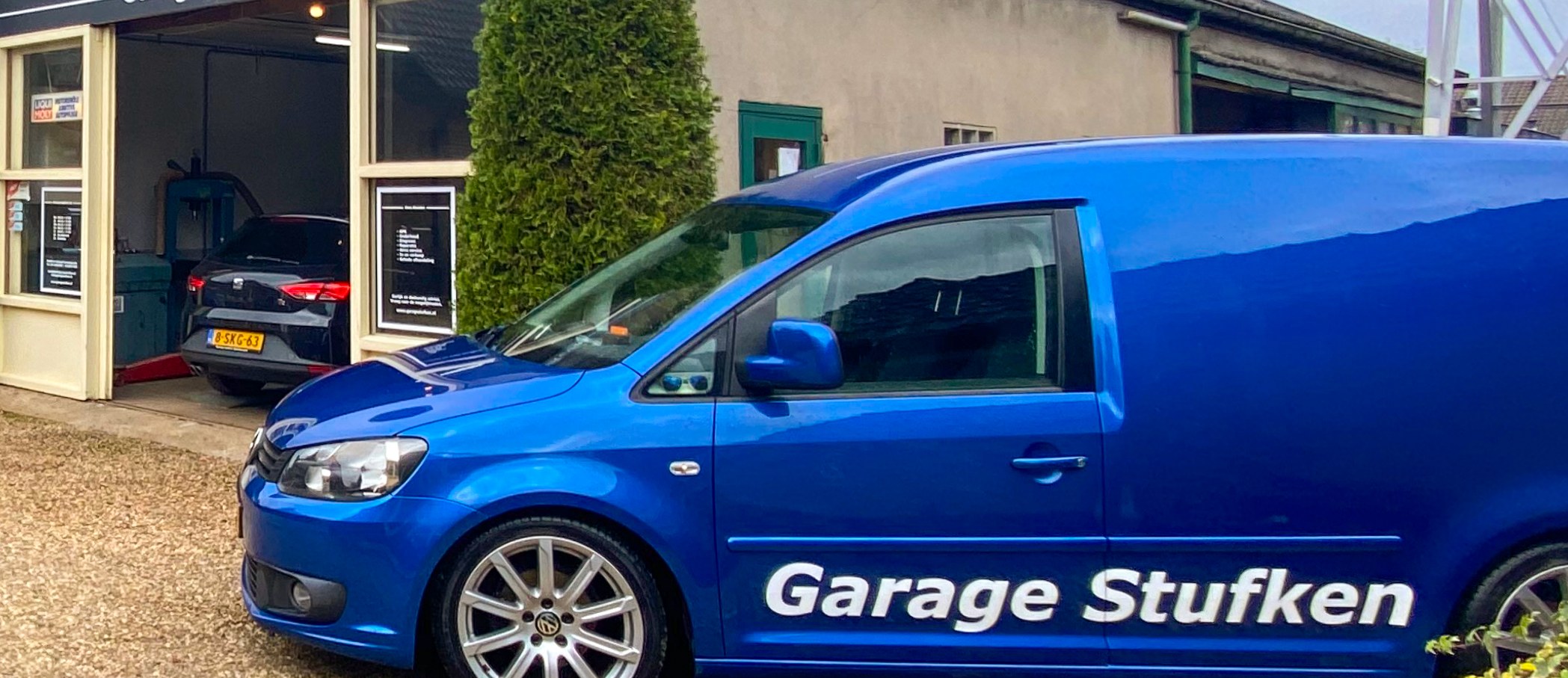 De blauwe Volkswagen Caddy met belettering Garage Stufken voor de garage